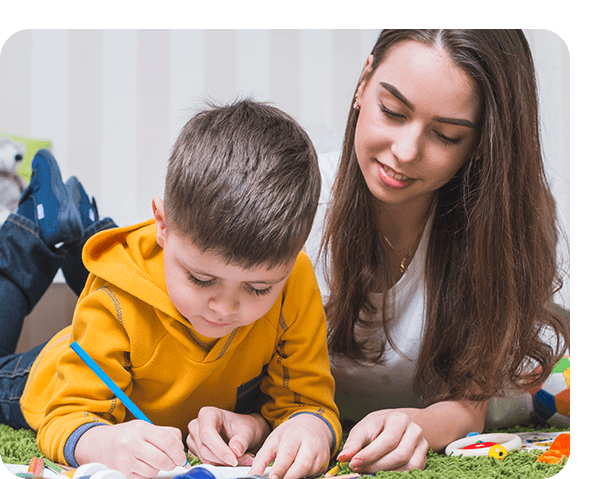A teacher helping a young boy with a drawing